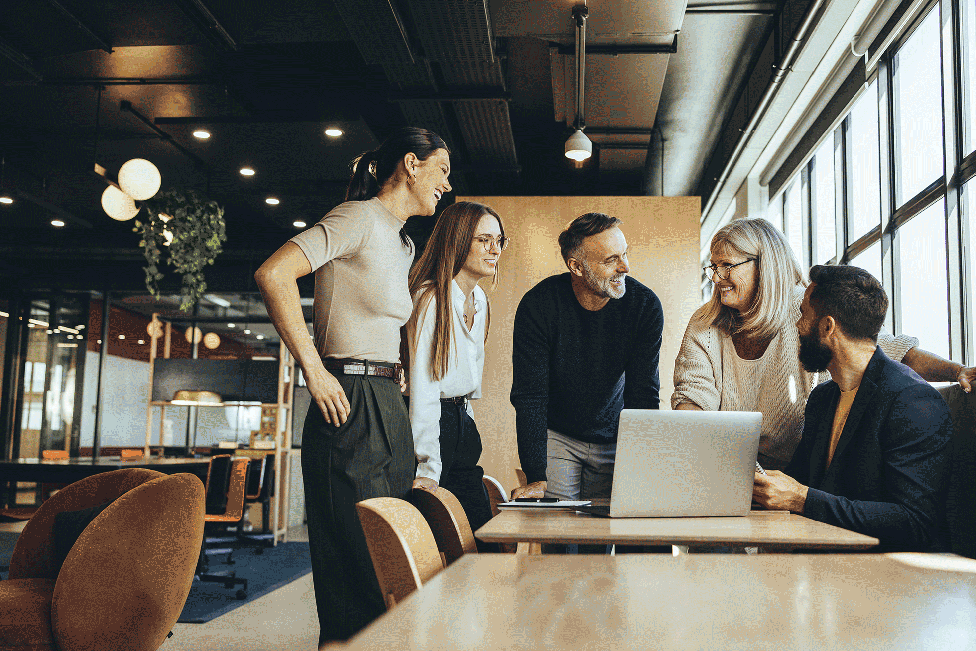 An image that shows group of people standing around a table in a workplace